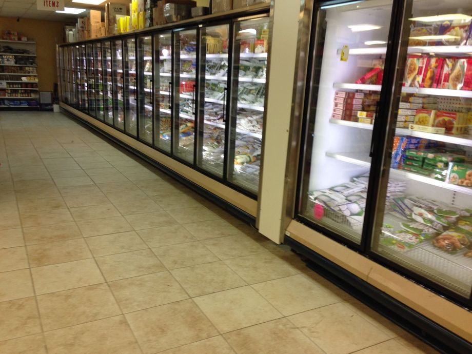 The inside of a grocery store with lots of fridges and shelves