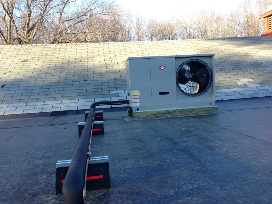 A large air conditioner is sitting on top of a roof.