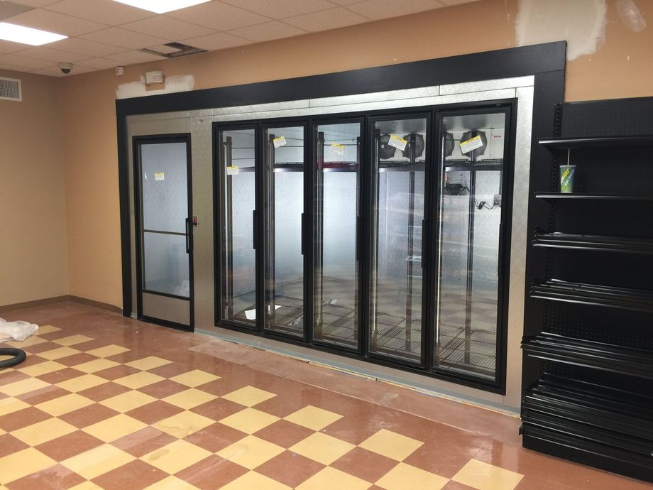 An empty room with a checkered floor and a refrigerator.