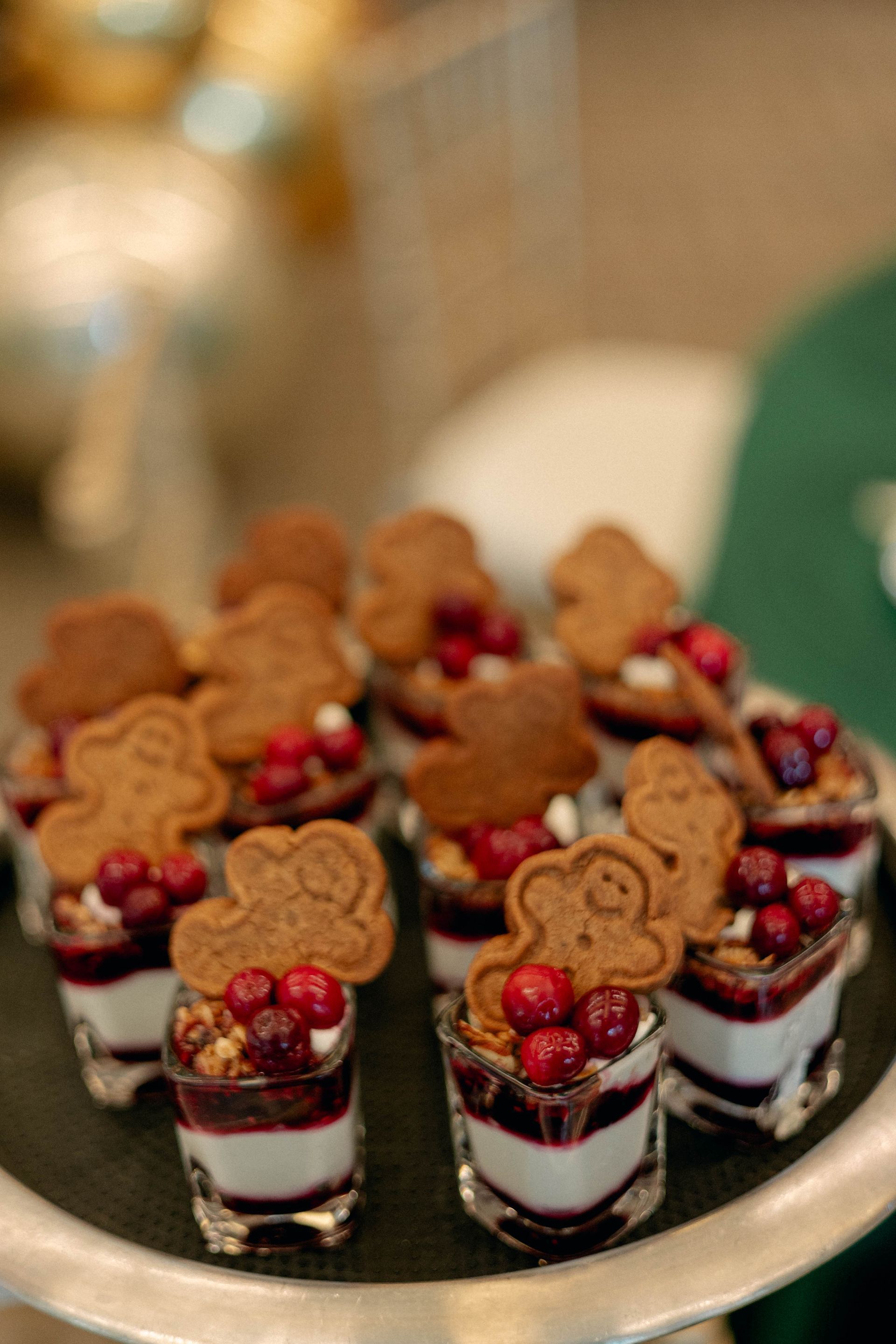 Tray of mini desserts: layers of cream, berries, granola, and gingerbread cookies.