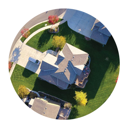 Aerial view of suburban houses with lawns, trees, and a curved driveway in a circular crop