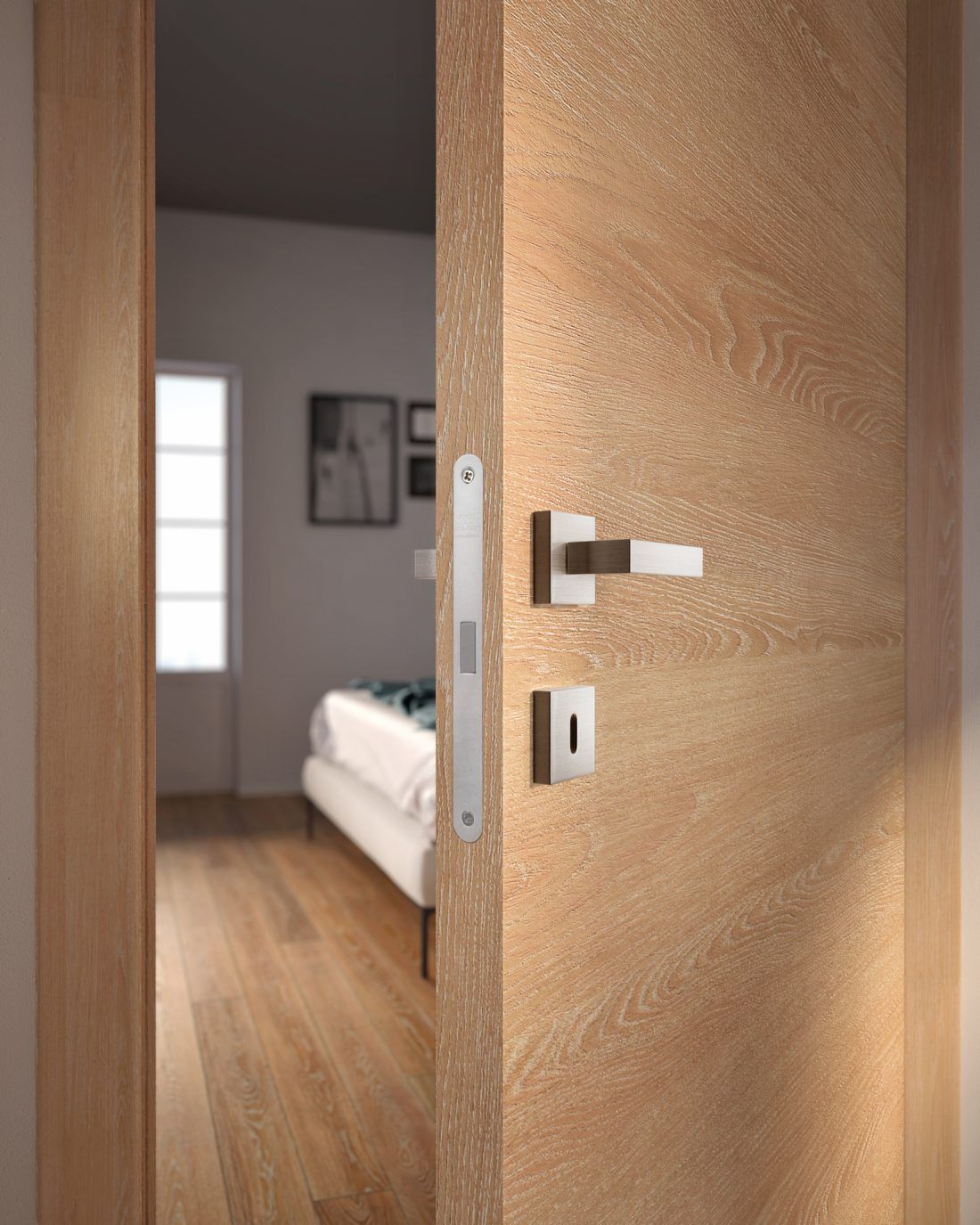 Una porta di legno parzialmente aperta rivela una camera da letto con un letto bianco e una finestra all'interno.