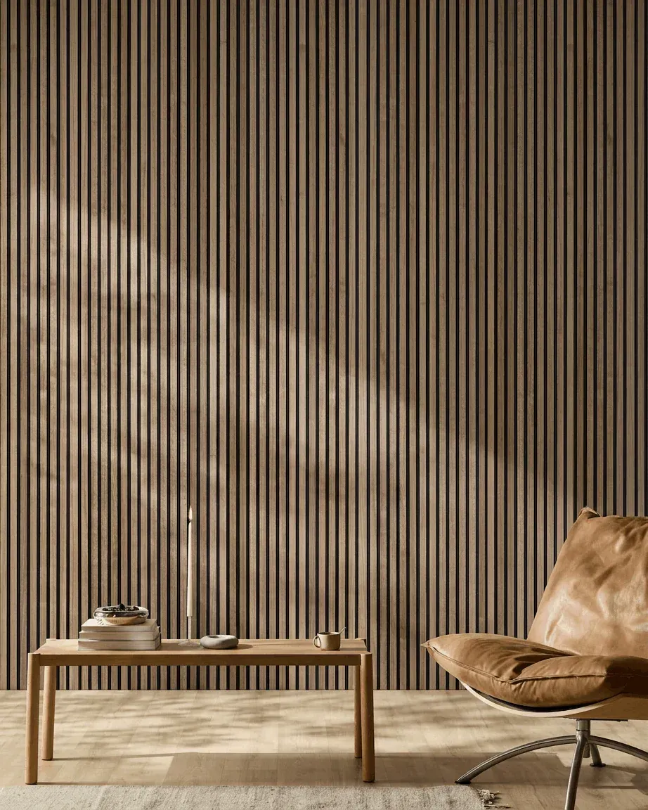 Soggiorno minimalista con parete a pannello fonoassorbente, tavolino basso e poltrona color cuoio in luce calda