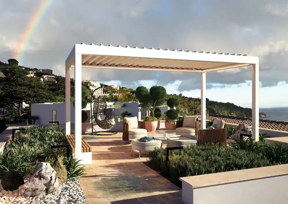 Moderno giardino pensile con pergola bioclimatica bianca, piante in vaso, posti a sedere e vista sulla città al tramonto.