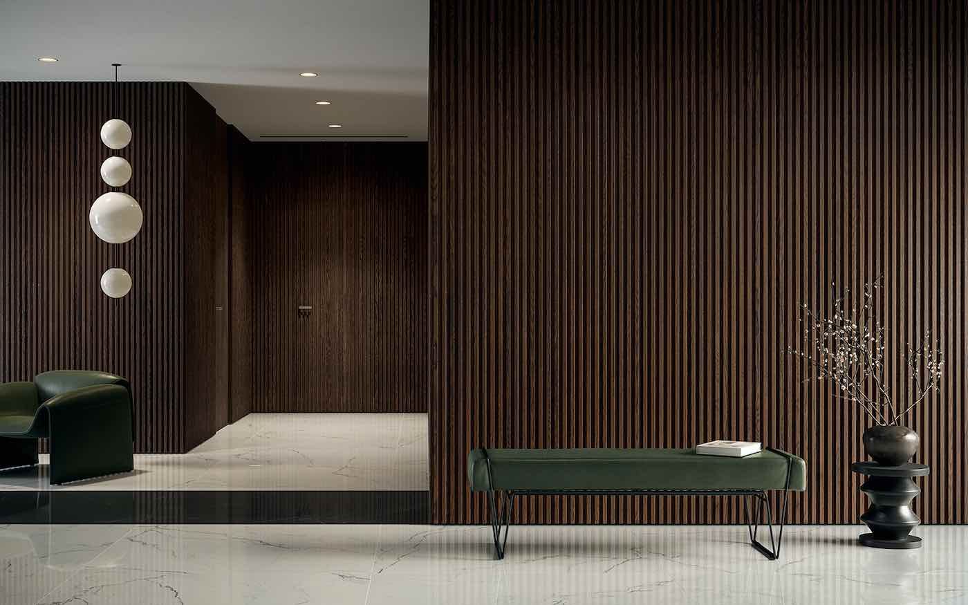 Atrio moderno con pareti rivestite in listelli di legno scuro, panchine verdi e applique rotonde.
