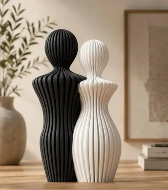 Stampa 3D, decorativi a busto con superficie scanalata, uno nero e uno bianco, su un tavolo di legno all'interno