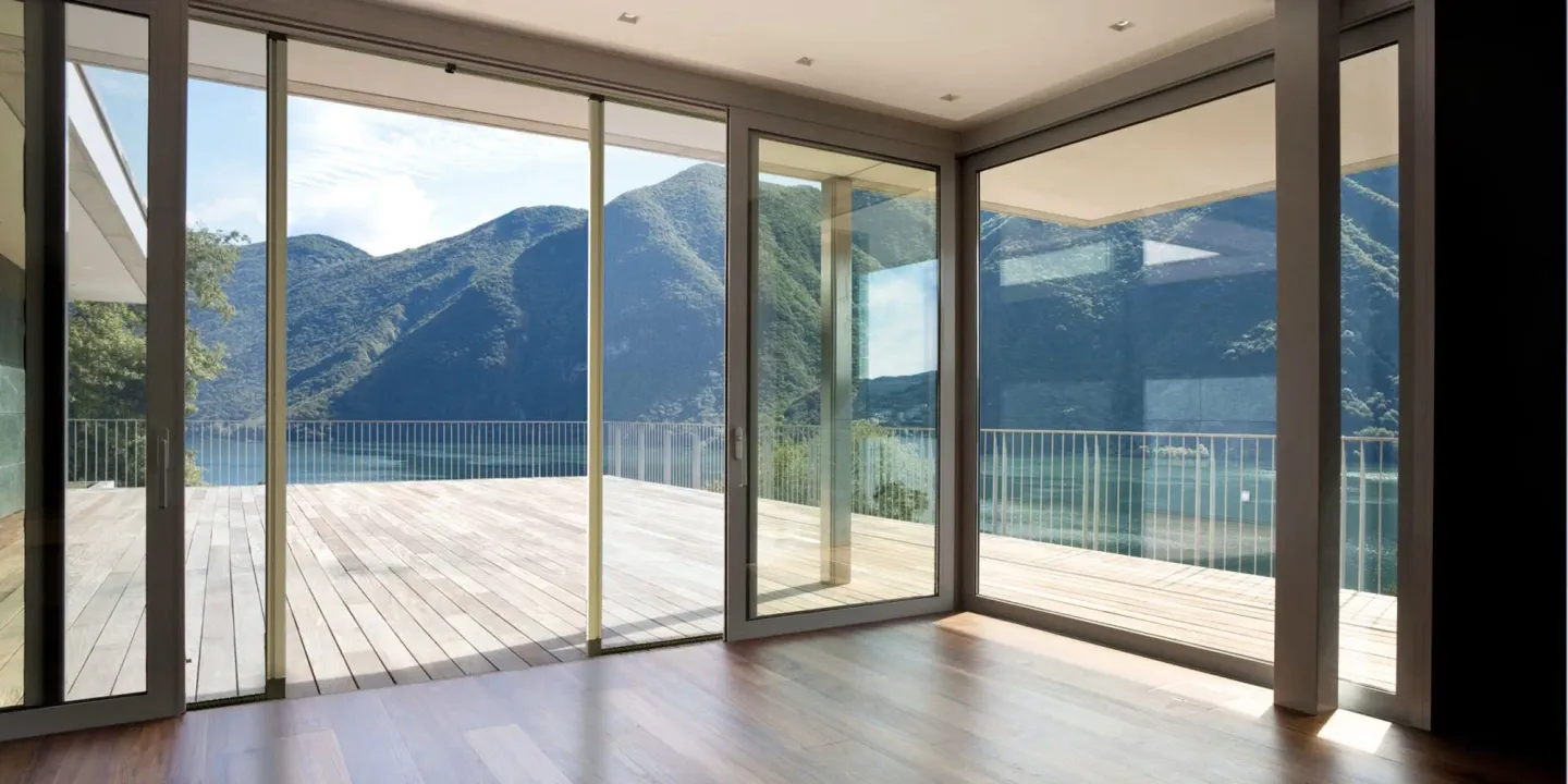 Vetrate con zanzariere, vista sulle montagne e sul lago e terrazza in legno esterna.