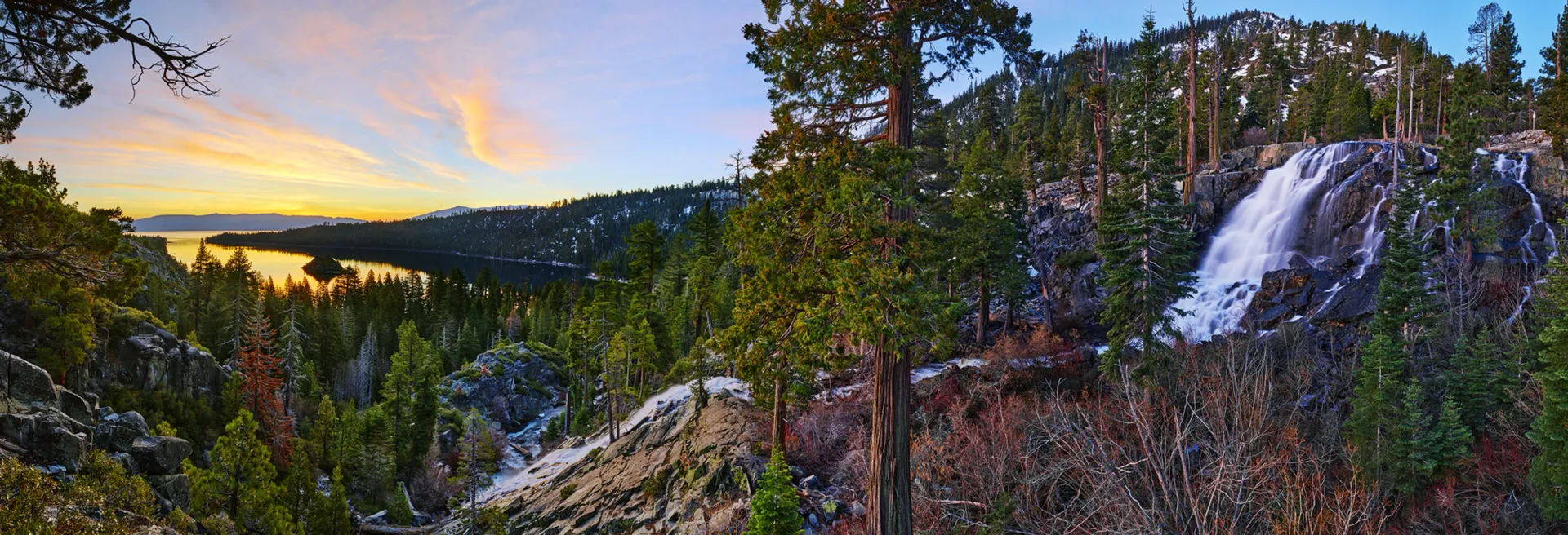 Mountain valley at sunset with a waterfall, forested cliffs, and colorful autumn foliage