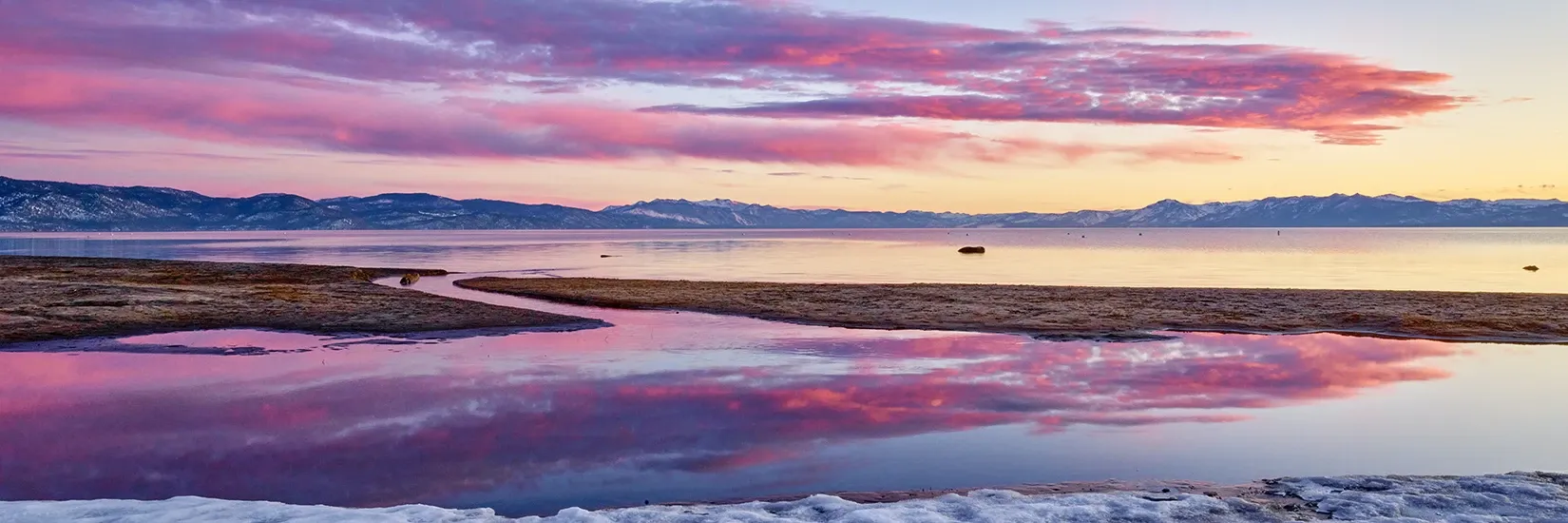 Colorful sunset sky reflected on a calm shoreline and wet sand