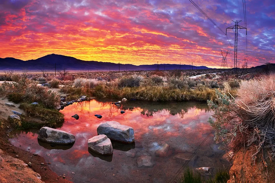 Sunset over a rocky wetland with vivid pink clouds reflected in calm water