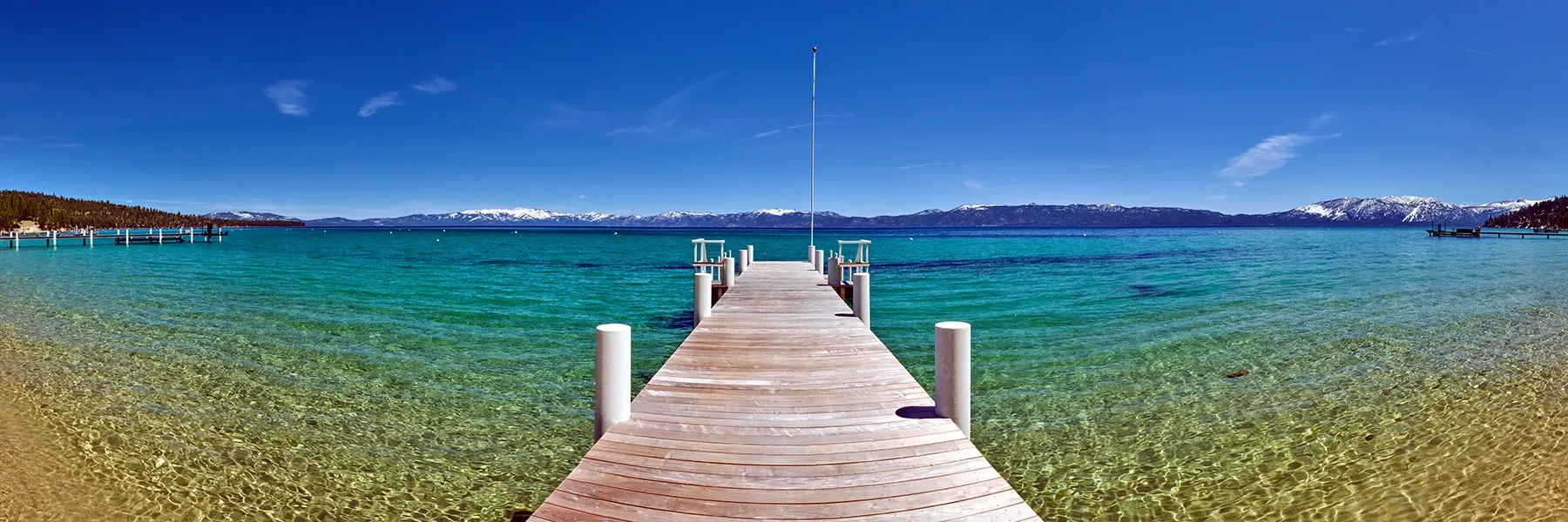 Wooden pier extending into clear turquoise water under a bright blue sky