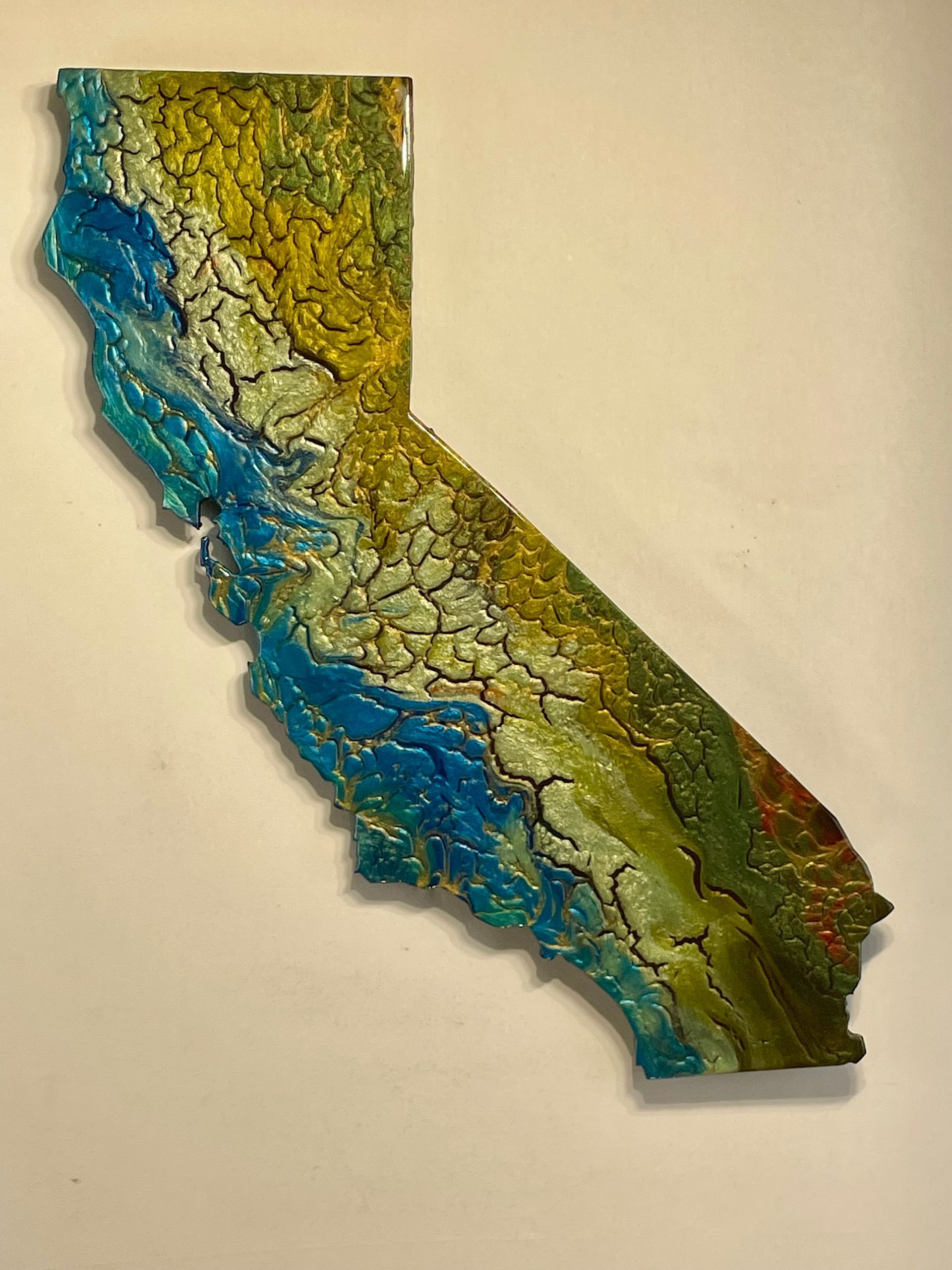 Textured wall art shaped like California, in blue, green, and yellow tones.
