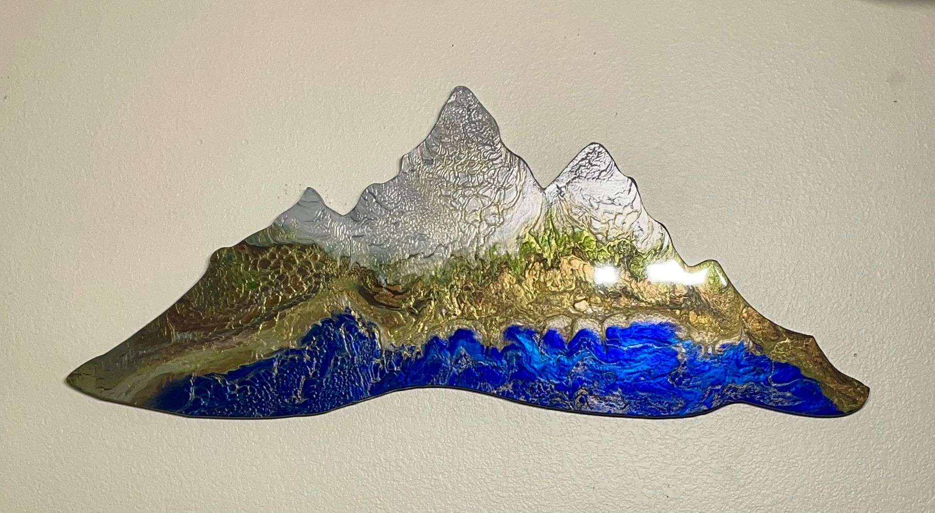 Decorative mountain-shaped glass wall art with blue, green, and silver colors