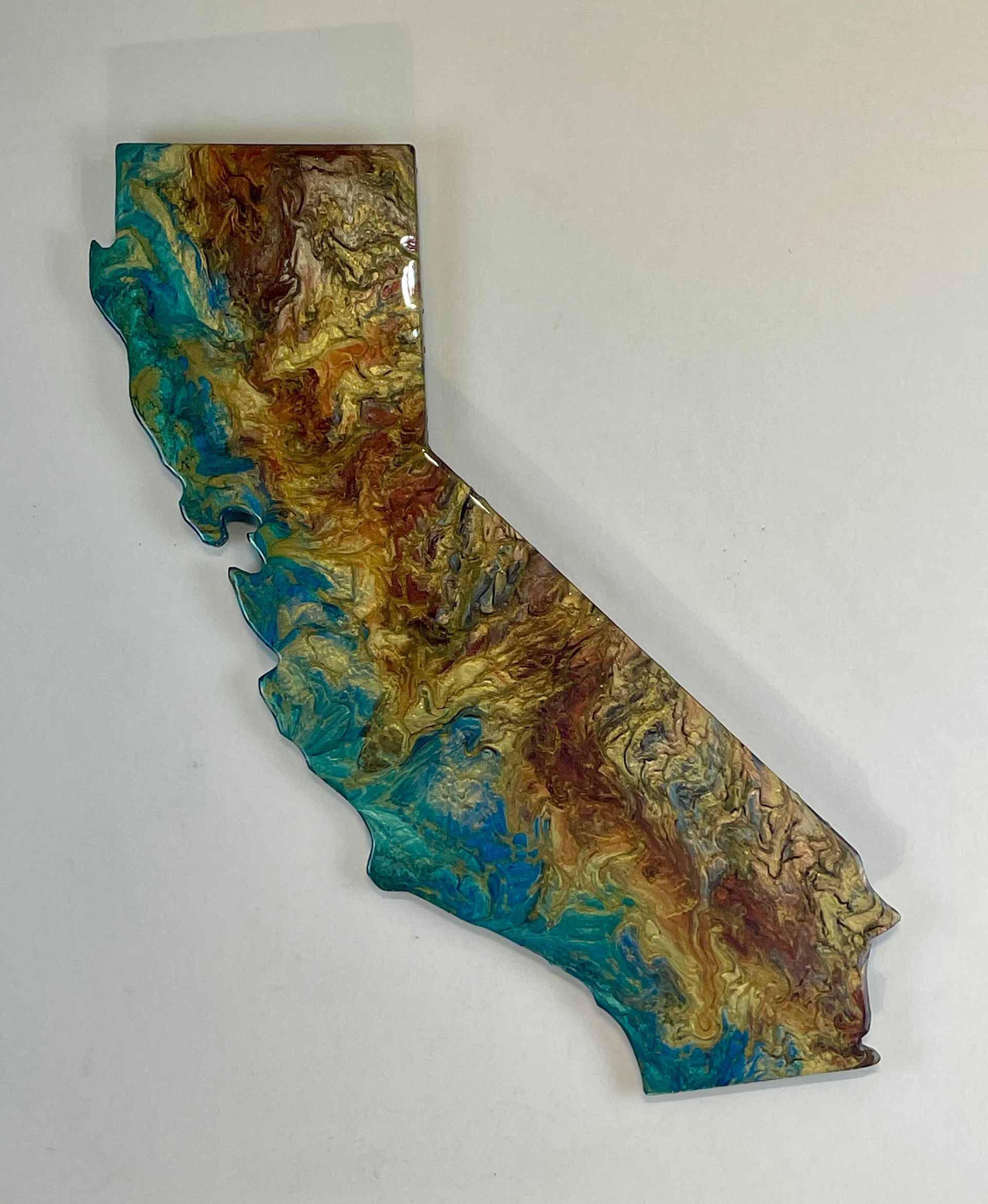 Colorful relief map of California in blue, green, brown, and gold on a white background