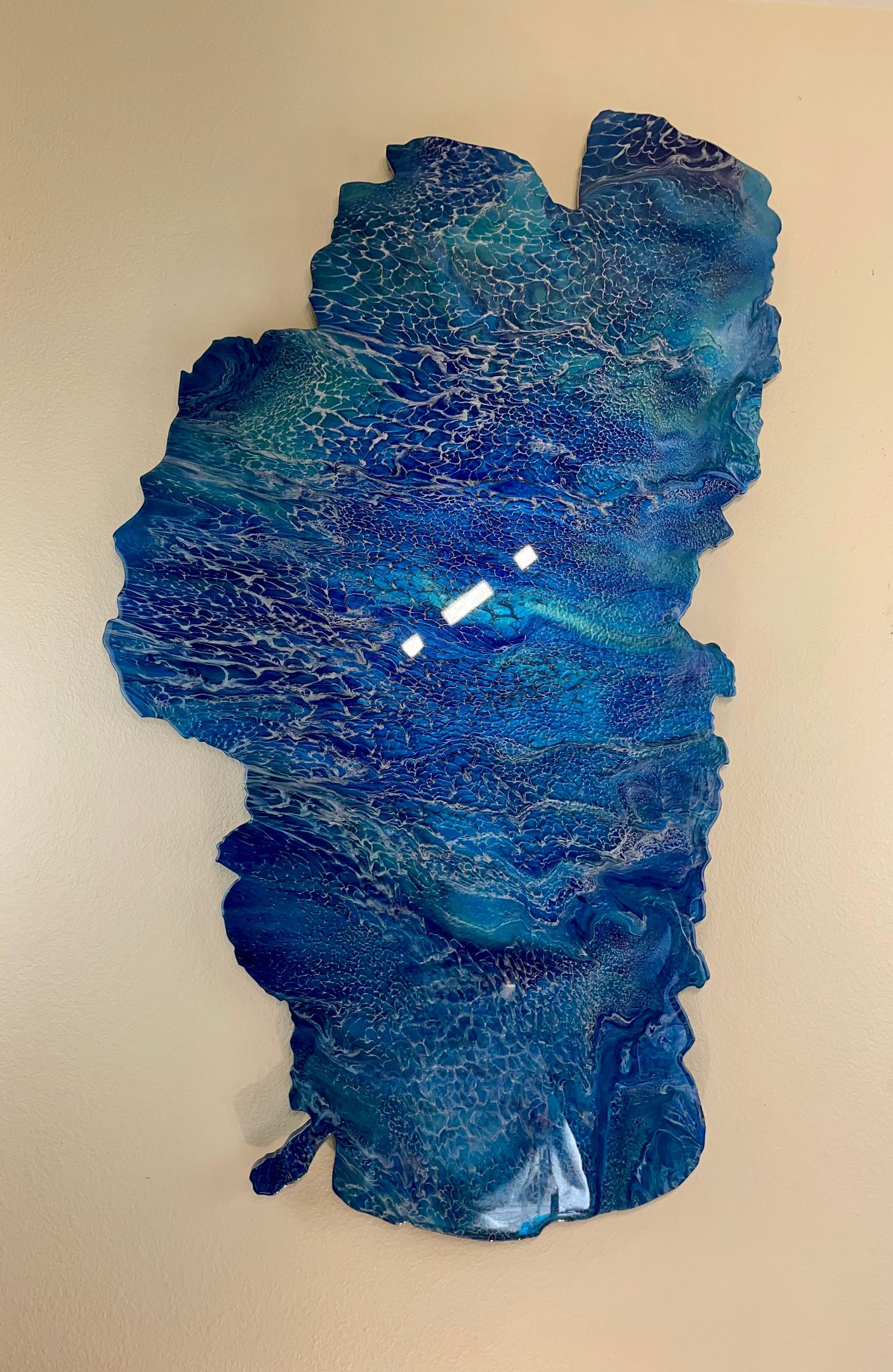 Blue glittery abstract sculpture or fabric form against a beige background