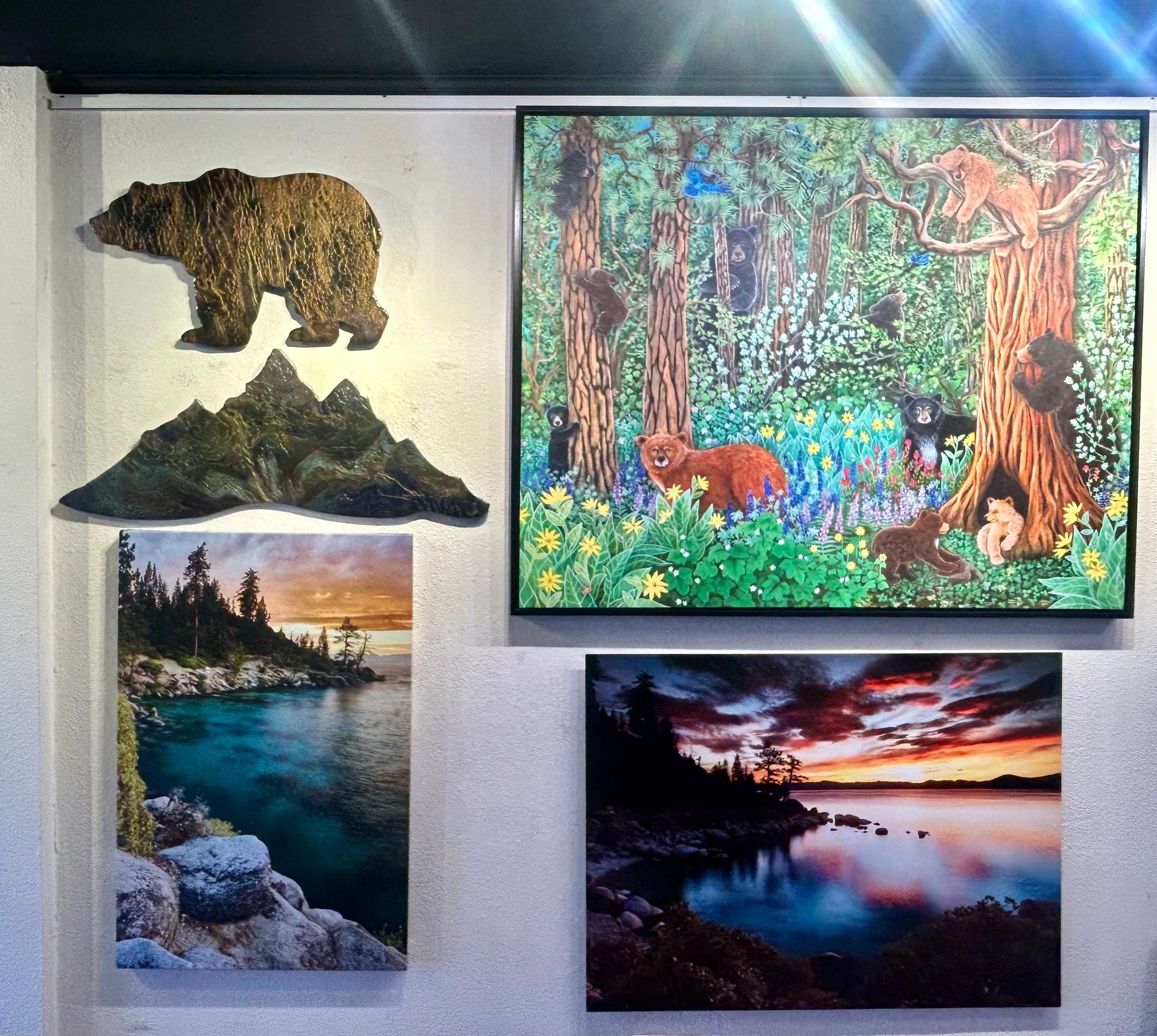 Wall of framed wildlife and landscape art, including a bear, forest scene, and sunset lake views