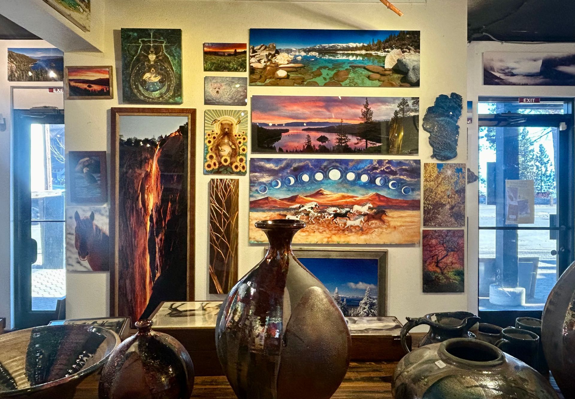 Art gallery wall with colorful landscape paintings and ceramic vases in the foreground