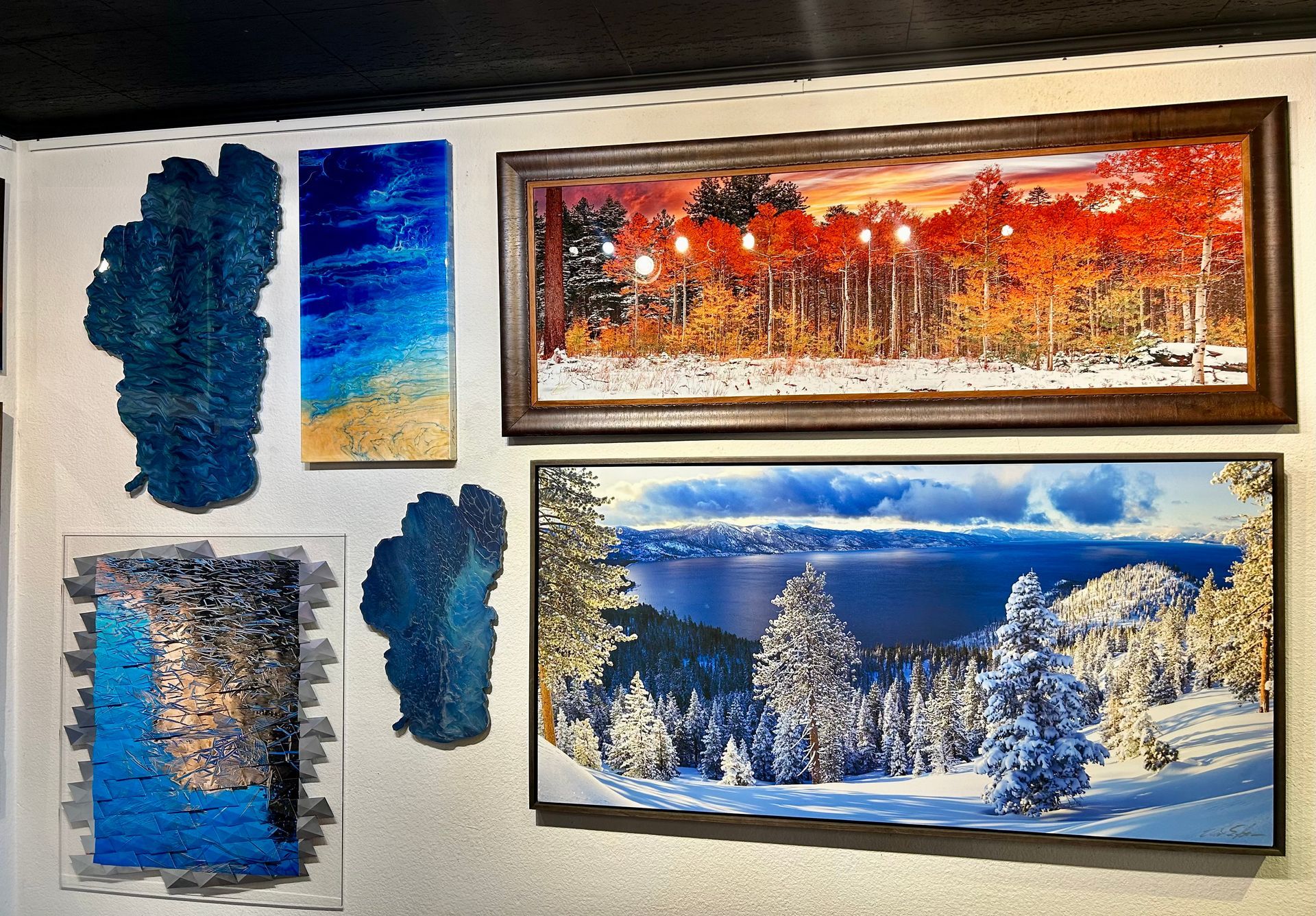 Framed abstract and landscape art on a wall, including snowy blue scenes and a red sunset panorama