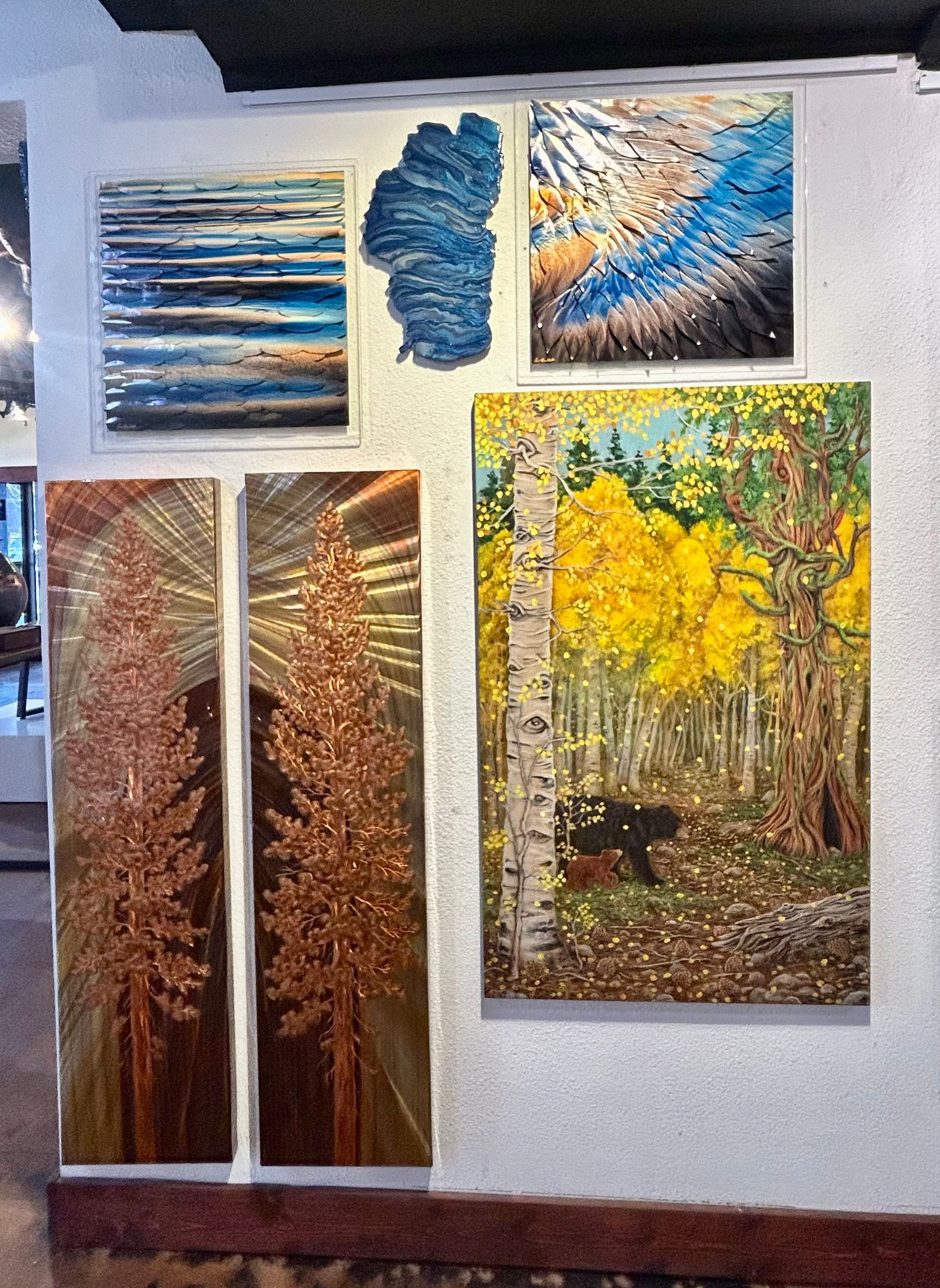 Wall display of abstract and forest paintings in blue, brown, and yellow tones