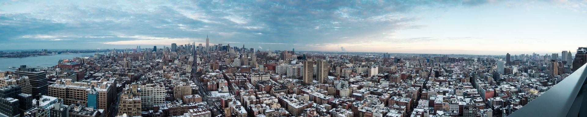 Panoramic city skyline with dense buildings under a cloudy blue sky at dusk