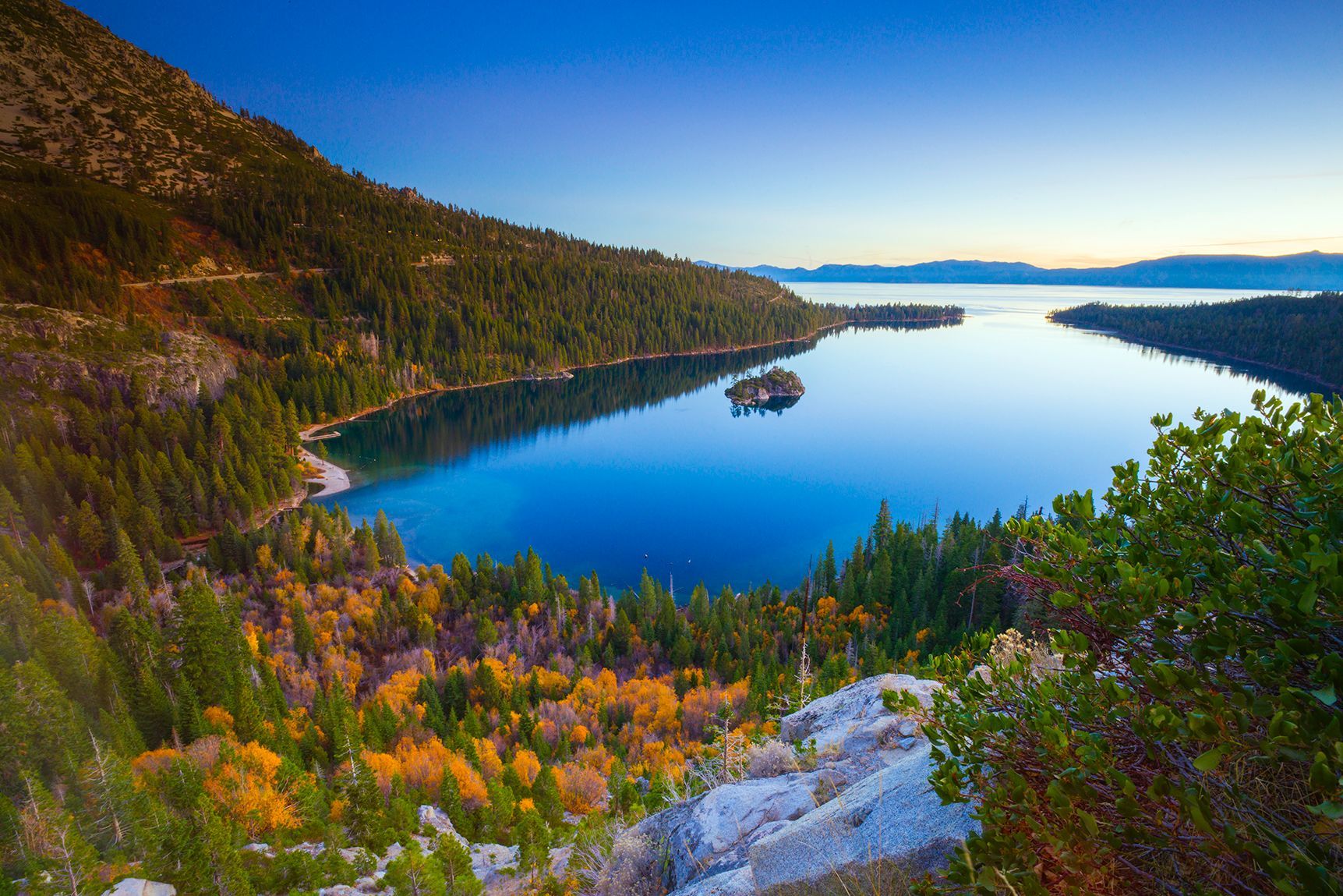 Colorful autumn forest overlooking a calm blue lake at sunset