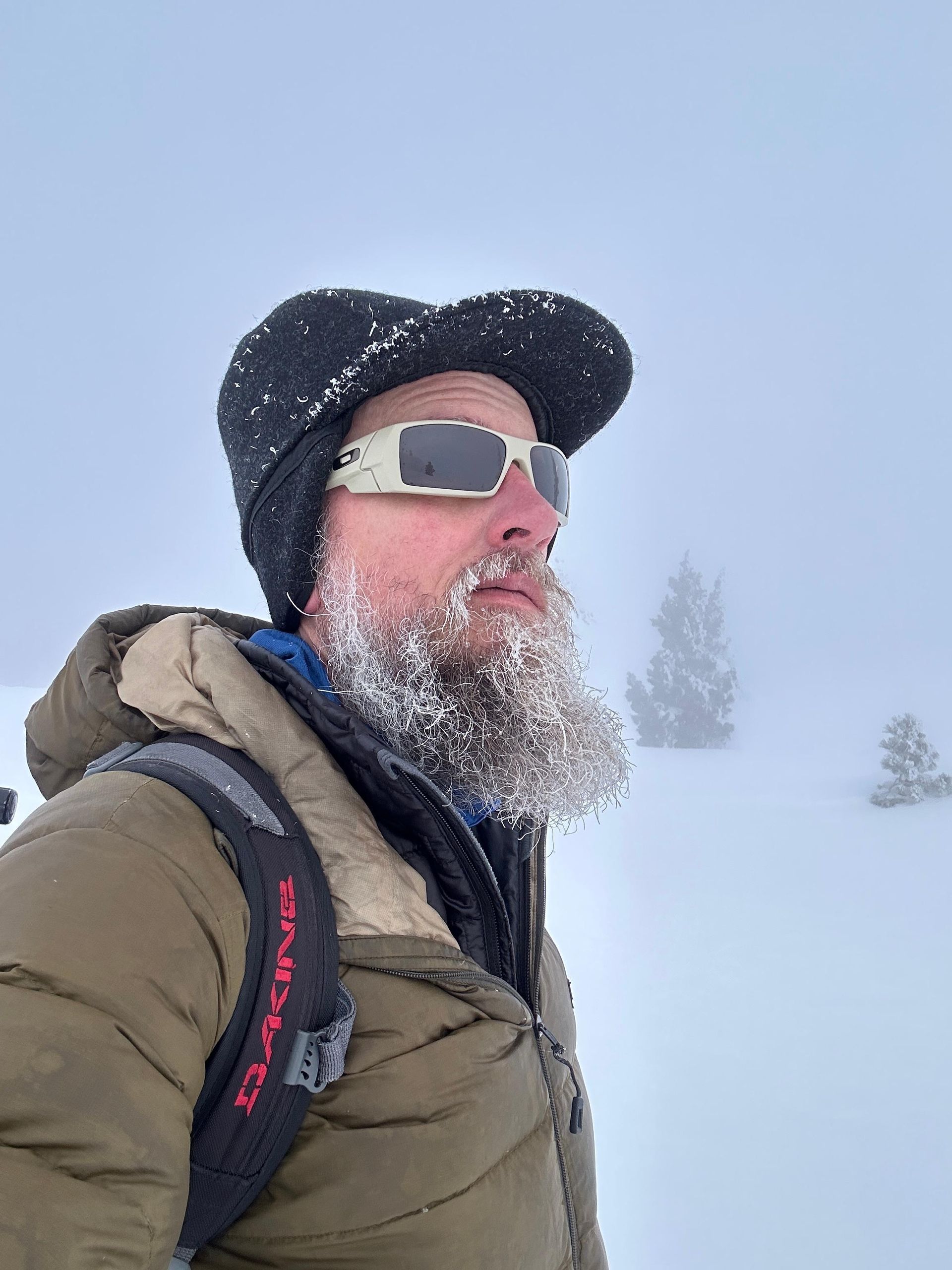 Snowy hiker in sunglasses and winter gear standing in a whiteout