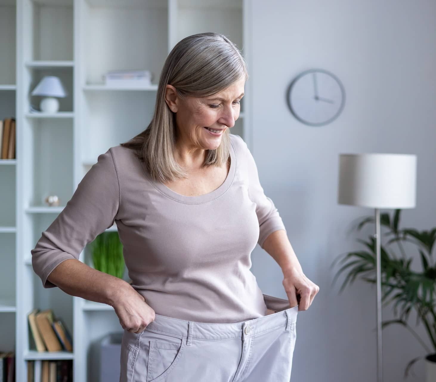 Woman trying on pants that are too loose for her because she has lost weight.