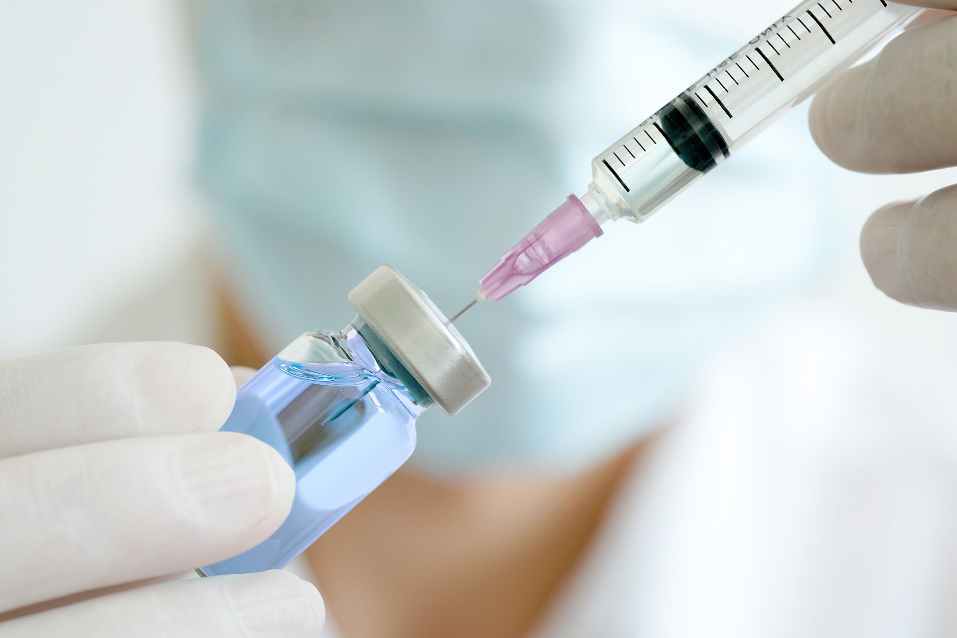 doctor's hand holds a syringe and a blue vaccine bottle at the hospital. Health and medical concepts