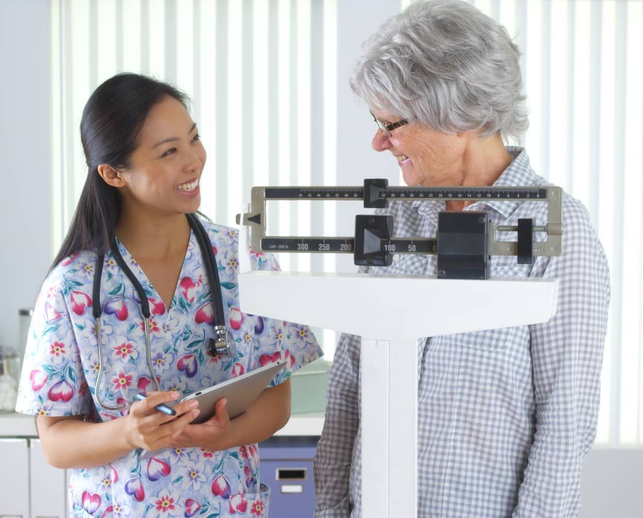 Woman standing on scale with doctor smiling at her