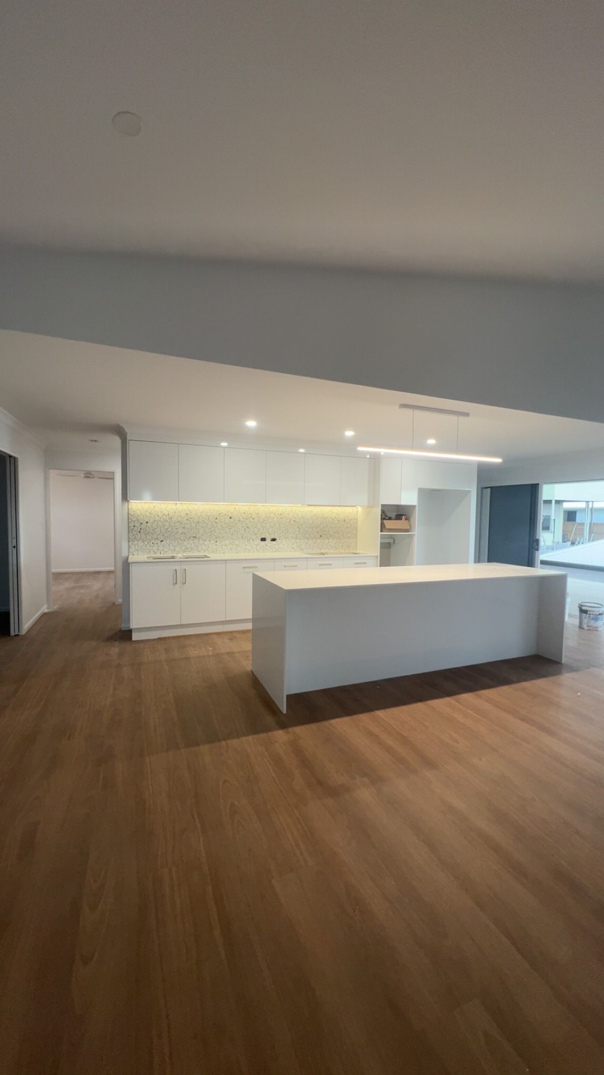 Modern kitchen with white island, wood floors, and bright recessed lighting