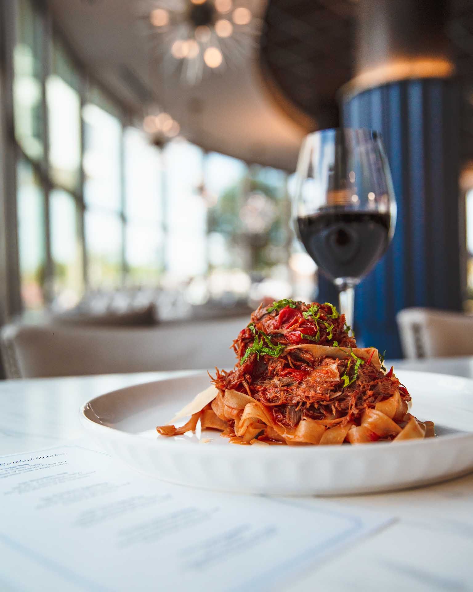 a plate of food with a glass of wine in the background