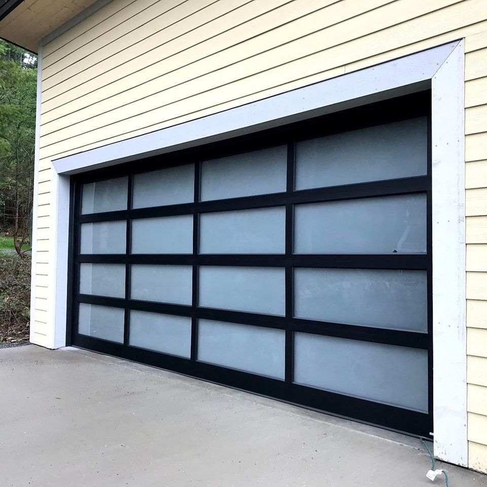 Modern black-framed frosted glass garage door set in a beige house exterior
