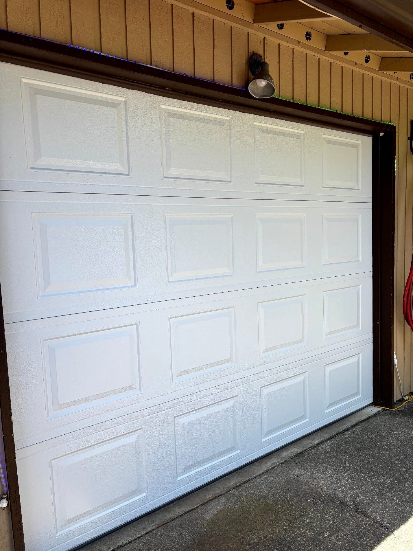 White paneled garage door beneath a brown eave on a concrete driveway