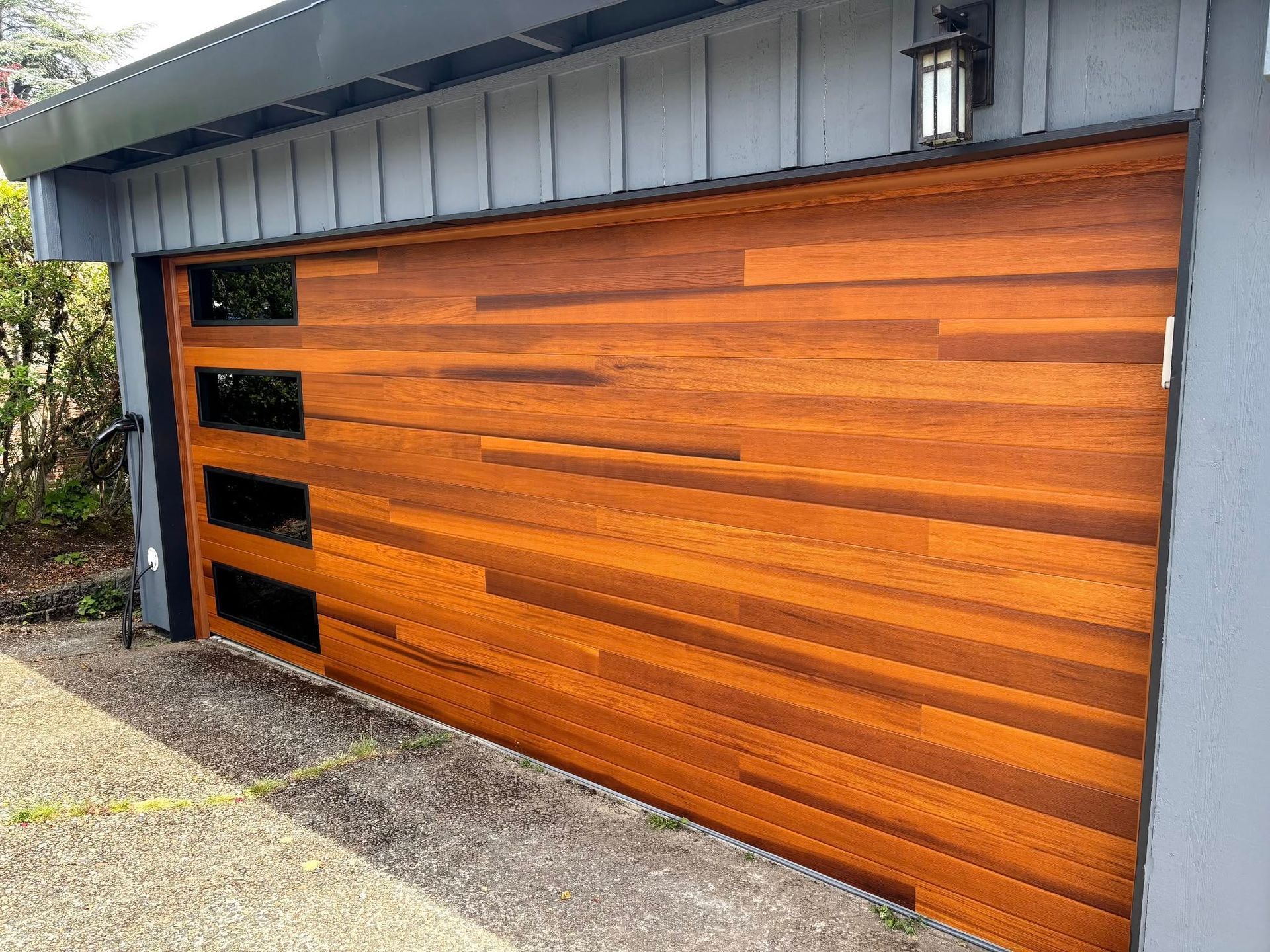 Orange wood garage door with four narrow black windows in a gray driveway facade