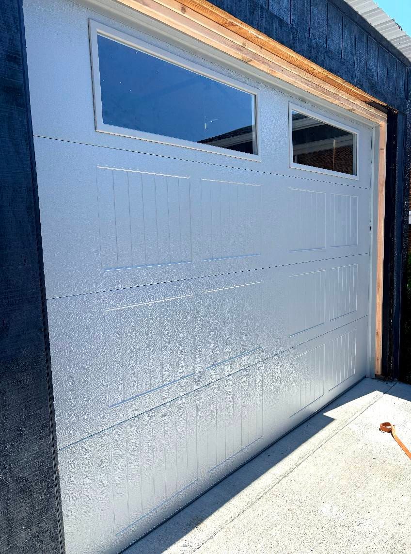 White garage door with two small windows, closed in bright sunlight.