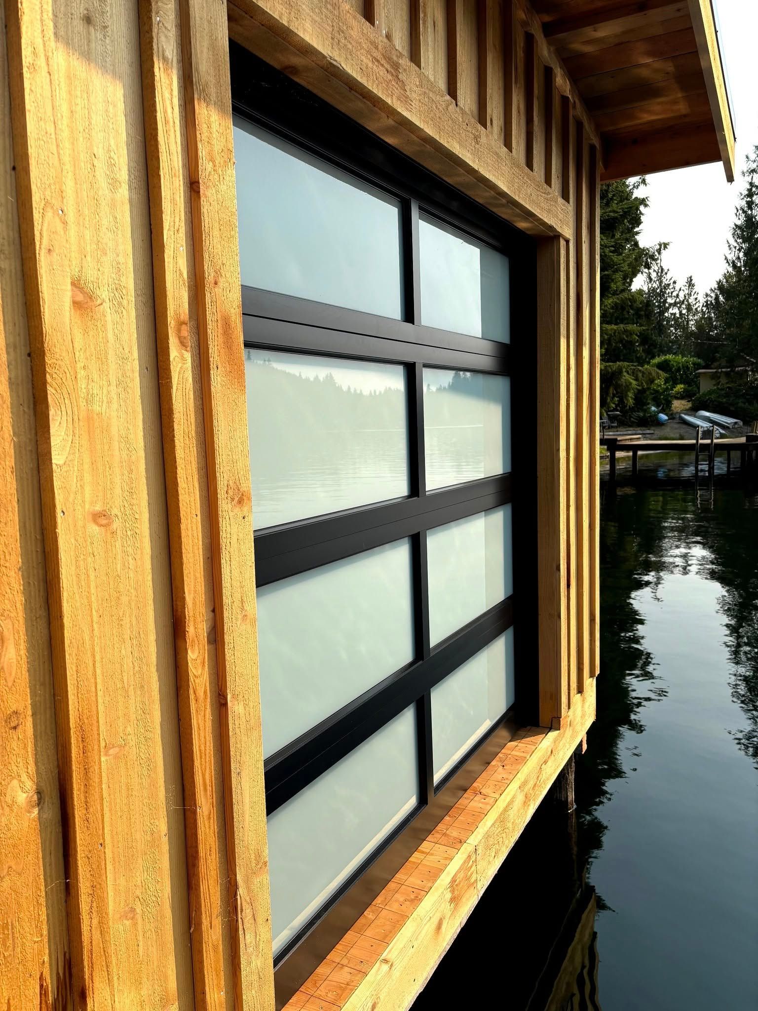 Wood-framed window with frosted glass overlooking a calm waterside scene