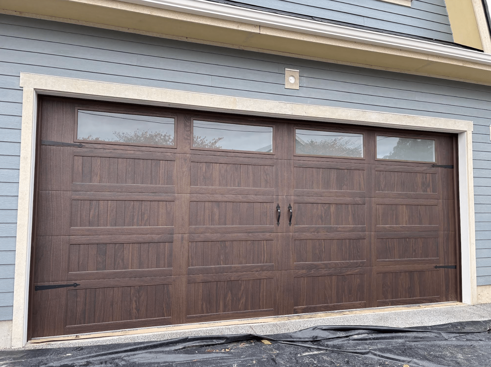 Brown three-car garage door on a beige house exterior