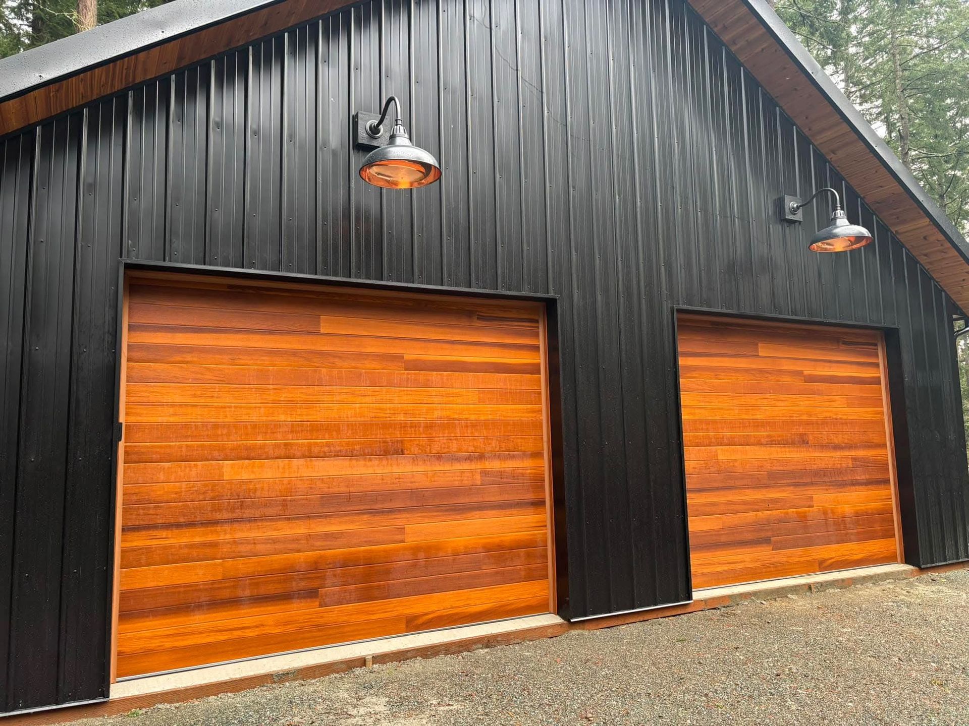Black barn-style garage with two orange wooden doors and exterior lights