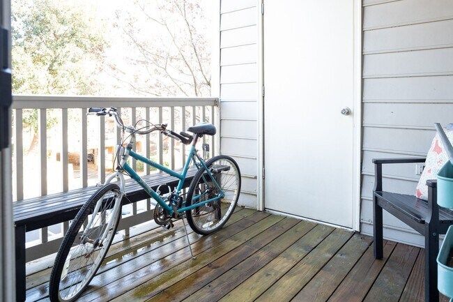 Teal bicycle leaning on a wooden porch beside a white door and black chair