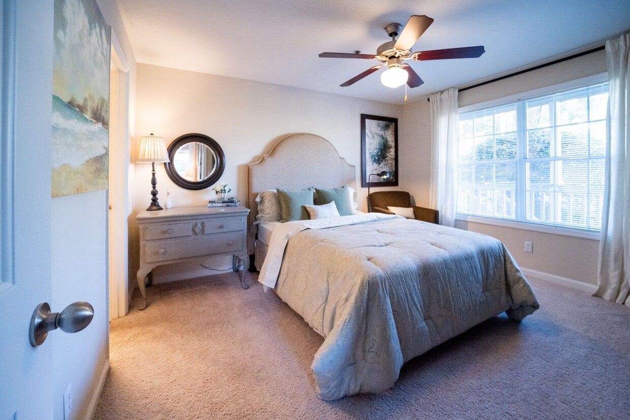 Bright bedroom with a bed, dresser, window, ceiling fan, and beige carpet