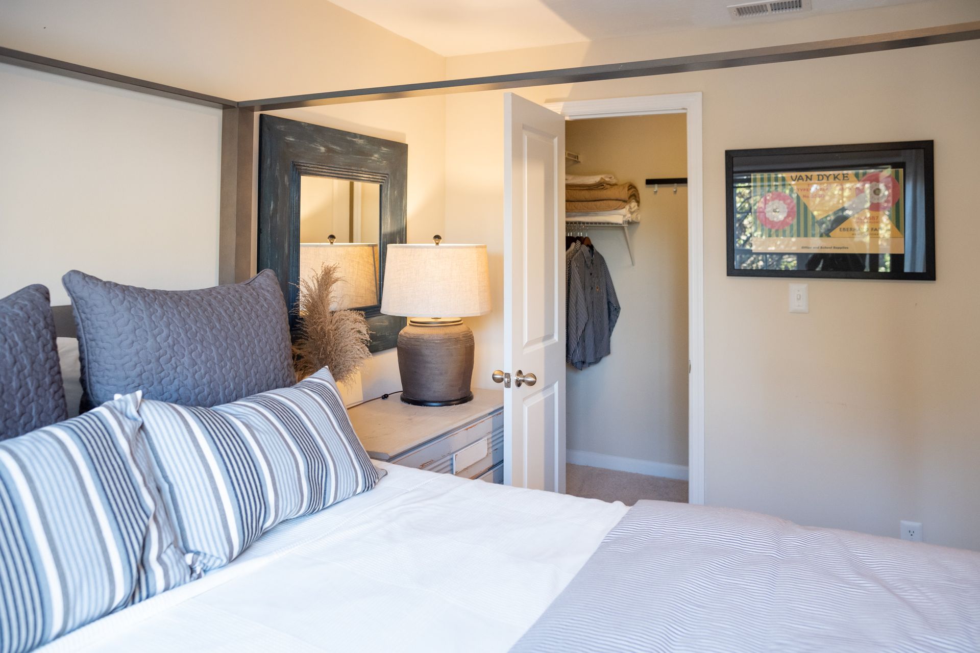 A bedroom with a bed , lamp , mirror and closet.