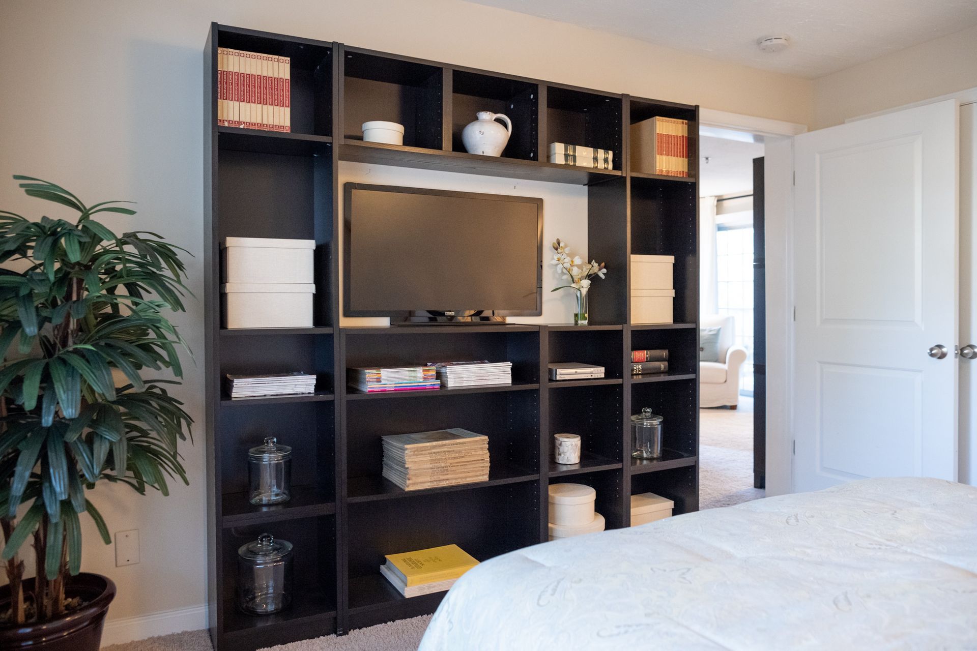 A bedroom with lots of shelves and a flat screen tv