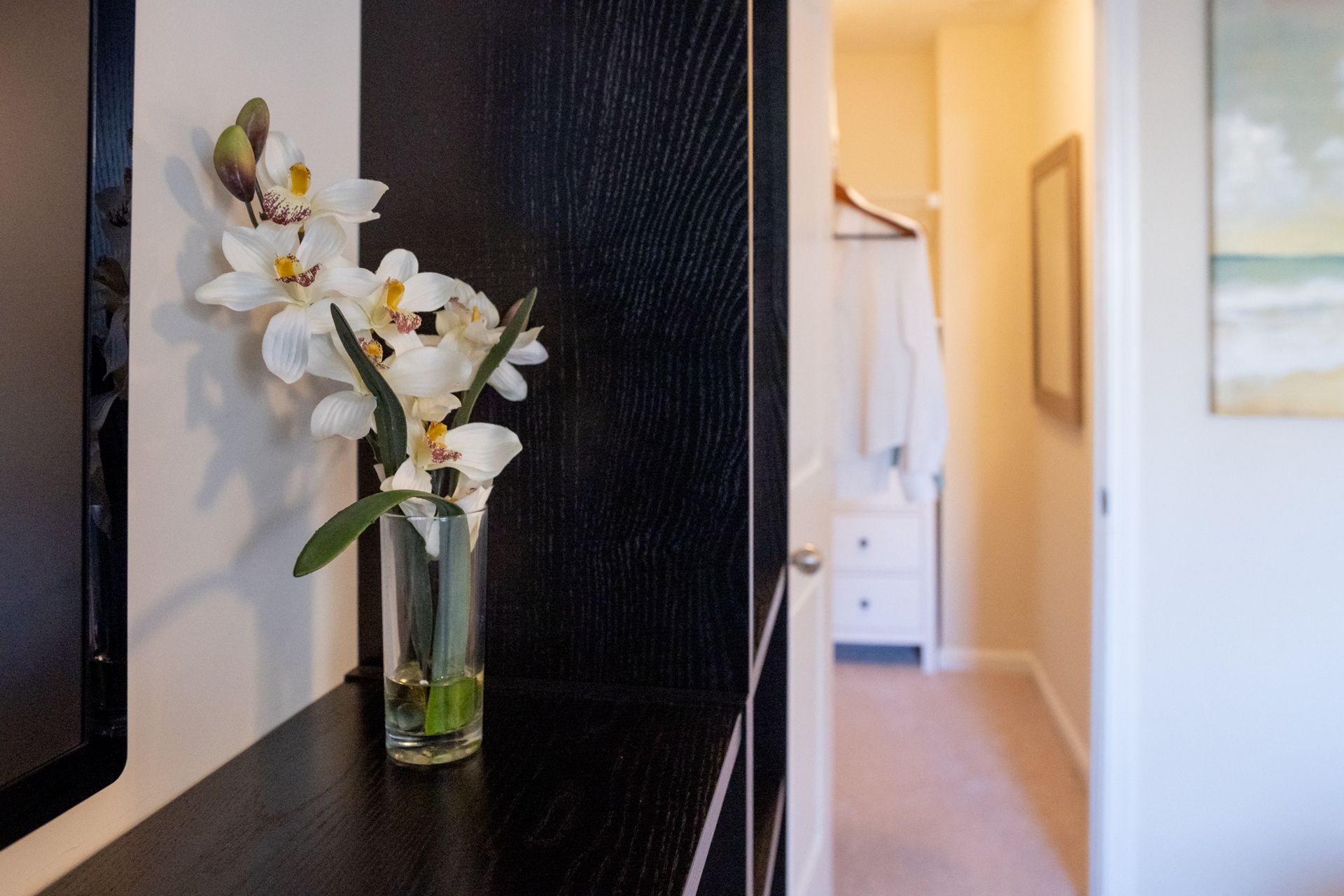 A vase of flowers sits on a shelf in a hallway.