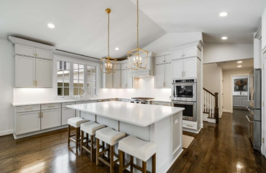 A kitchen with white cabinets and stools and a large island.
