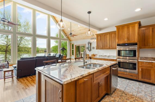 A kitchen with wooden cabinets , granite counter tops , stainless steel appliances and a large island.