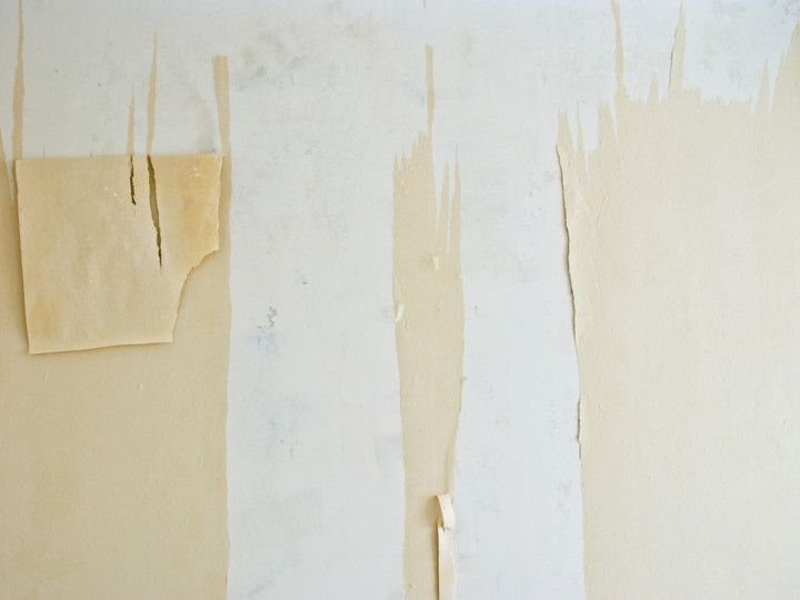 A photo of wallpaper being removed from a wall.