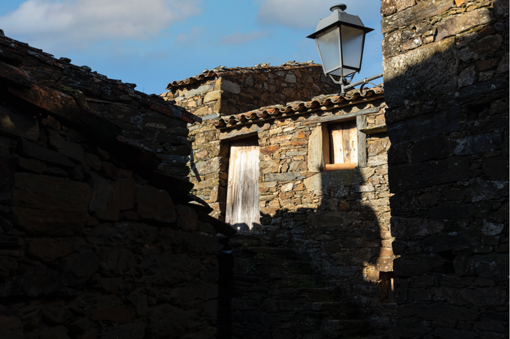 A sombra de um poste de luz é projetada em uma parede de pedra numa aldeia do xisto