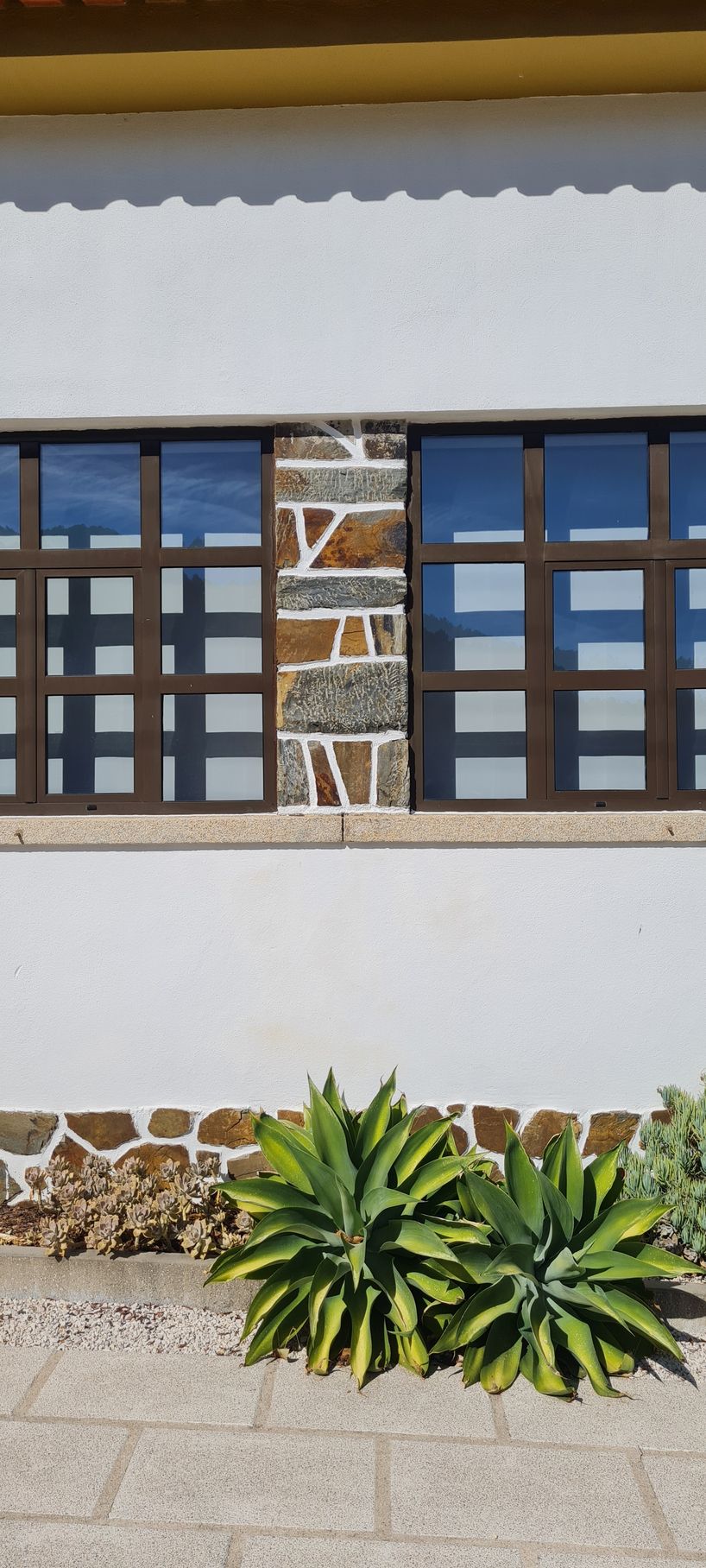 Fachada de uma casa com janelas em quadriculado, como as antigas escolas primárias em Portugal.