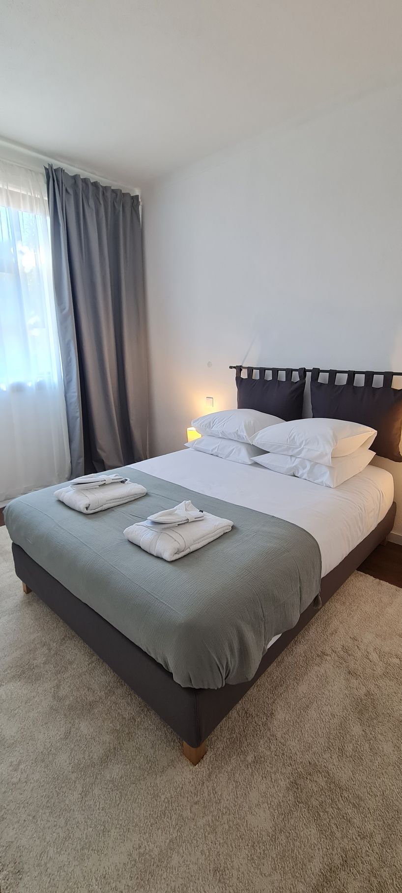 Quarto com cama de casal, carpete de pêlo curto, cortinados blackout e cortinados em organza. 