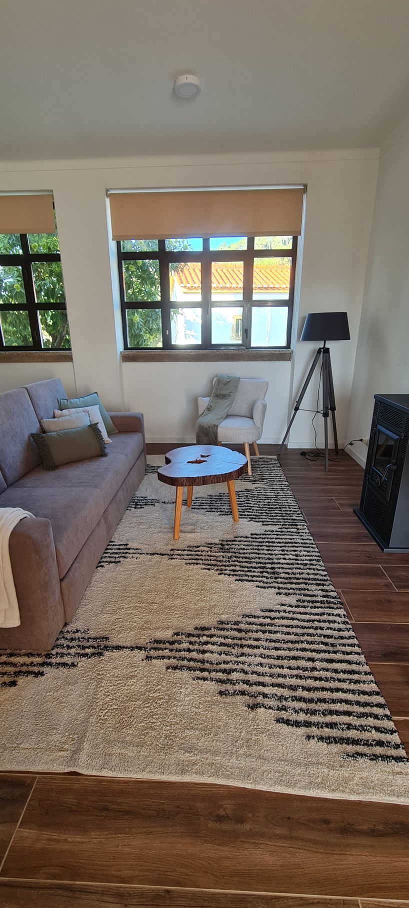 Sala de estar com um sofá, um cadeirão de leitura, uma mesa de centro, um candeeiro de pé e uma carpete de pêlo curto.